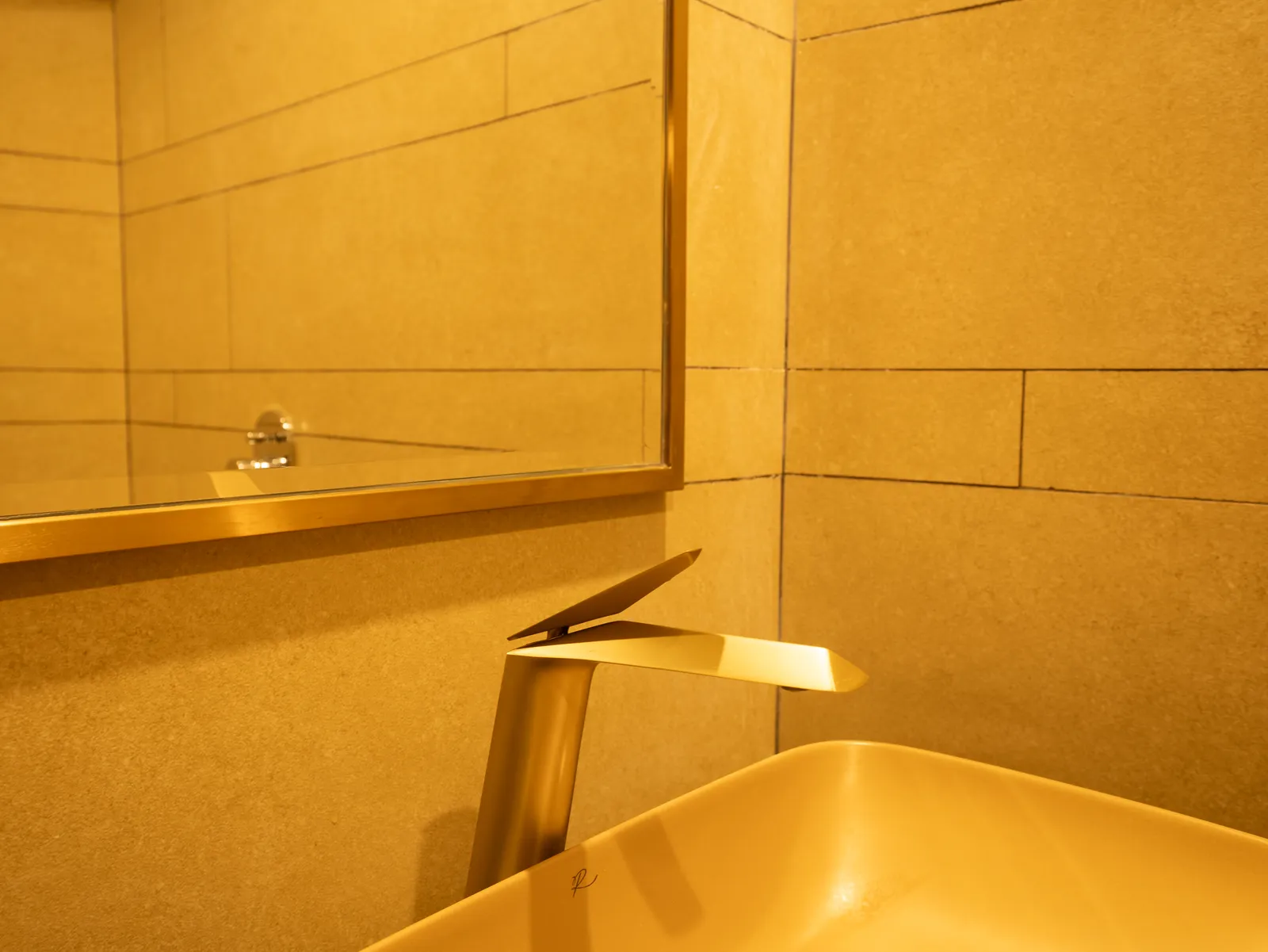 Washroom with gold mixer tap and stone wall — Chalukya Samrat
